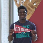 Victor holding up a Glen Burnie pennant while wearing an AACC shirt.