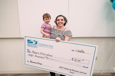 Daze Creamer Ellecamp holding a giant check with her baby.