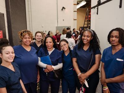 C.E.W.D. graduates in navy scrubs posing together.