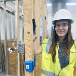 Mary in safety gear next to a construction frame.