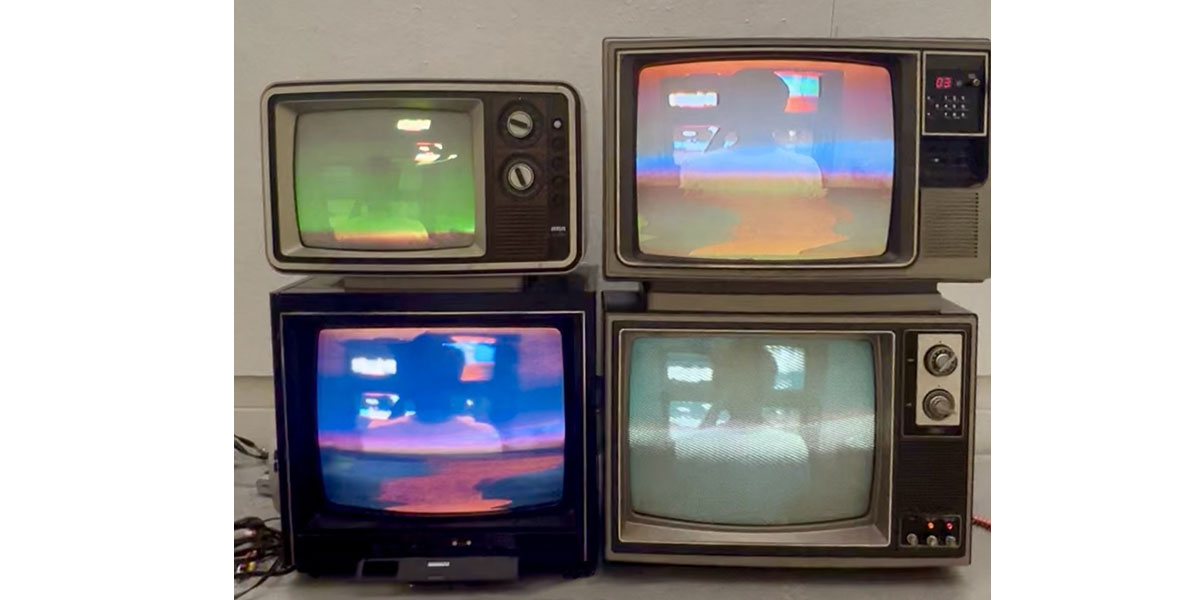 An art installation of four old TVs with an image of a person looking at four TVs in different colors.