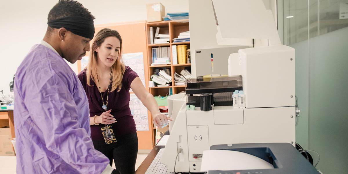 Instructor working with student in medical lab.