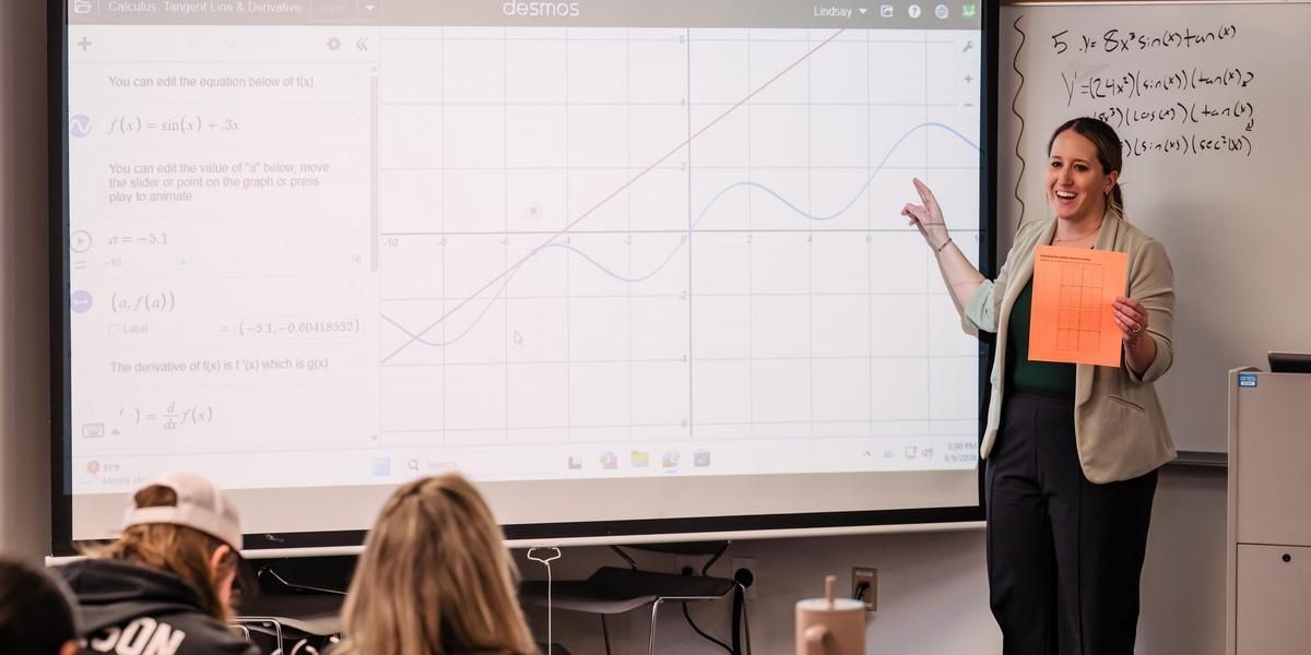 Professor Lindsay Roark stands in a classroom in front of a screen with a graph on it.