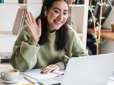 Online student waves at computer screen.