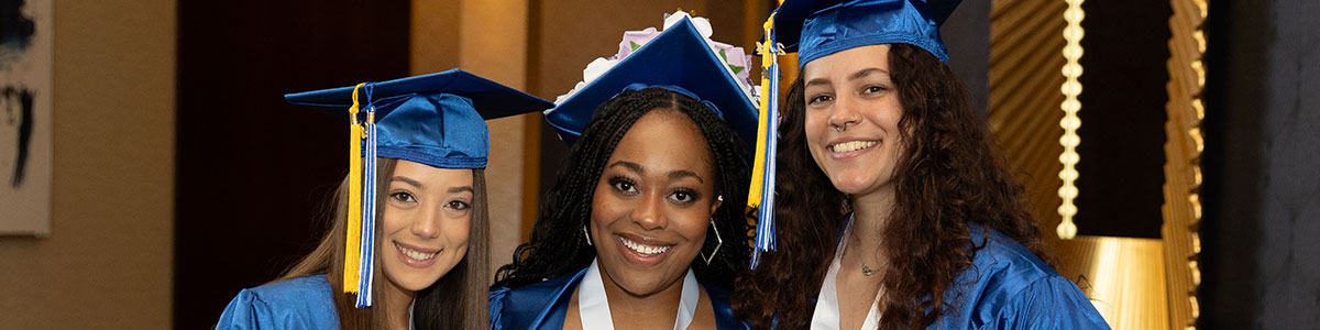 Three AACC graduates smiling at Commencement ceremony